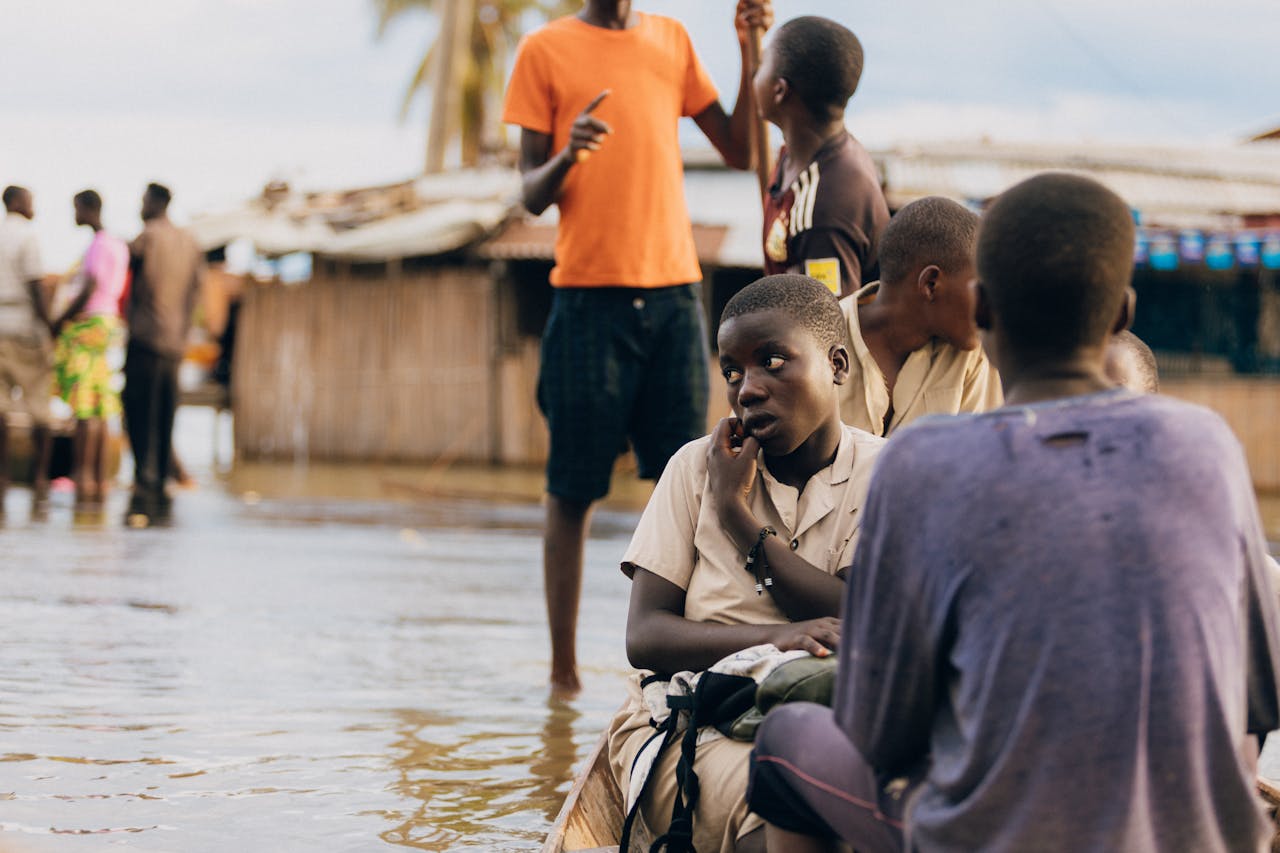 services-03 Children in rural village navigate flood waters, depicting resilience.