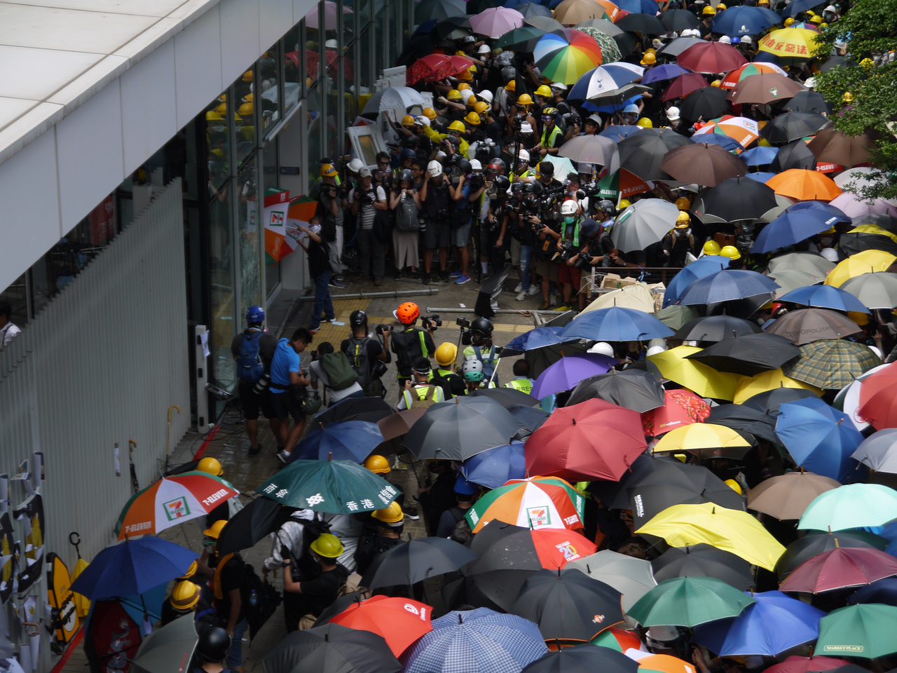 ours-journey Crowded square with group of protestants near facade of building in rainy weather waiting in front of entrance
