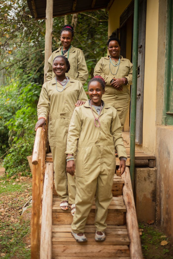 services-01 Four women in similar uniforms smiling on a wooden porch with greenery.