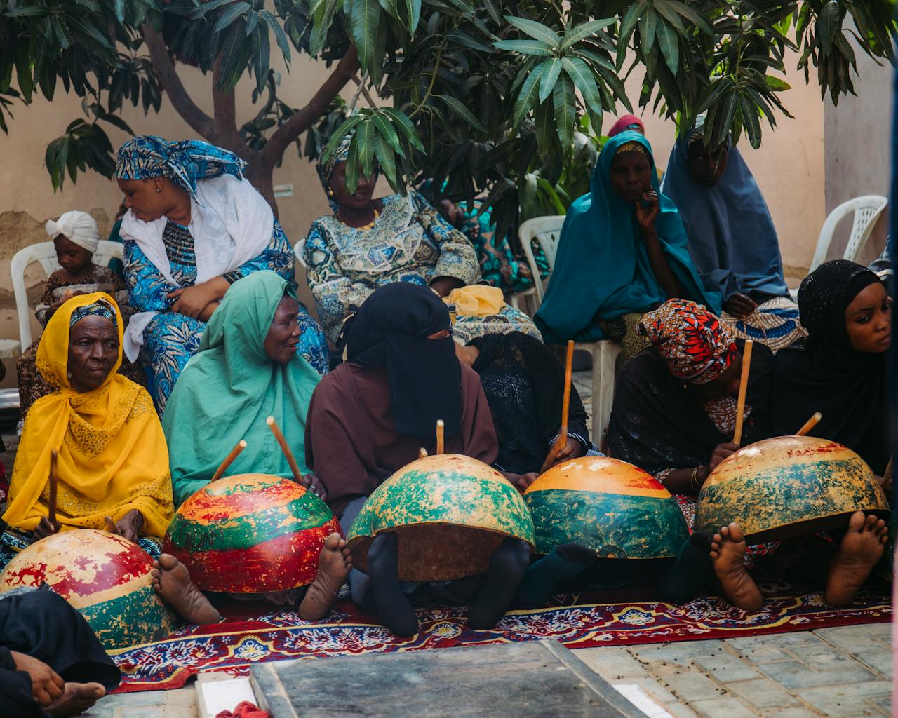 hero-img-01 Women in traditional attire gather for a cultural event in Kano, Nigeria, showcasing community traditions.